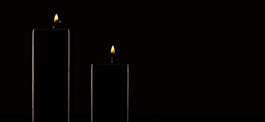 Burning black candle on dark