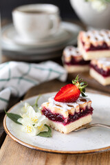 piece of tasty pie with strawberries on a white plate on ooden table.