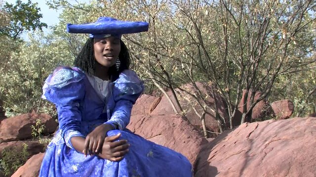 herero woman wearing a Victorian style dress outdoors in a village in north Botswana