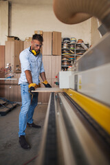 Woodworker operating on an edge banding machine making furniture