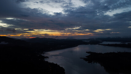 Aerial view of an amazing Colorful and Dramatic sunrise. Majestic Sunlight Cloud fluffy,Idyllic Nature Peaceful Background,Beauty Dark Blue Hour on Dusk,Purple Dawn Silhouette mountain on Kenyir Lake.