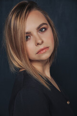 close-up portrait of a girl with short blond hair in a blue dress on a dark background