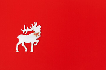 Fototapeta na wymiar Christmas greeting card with handmade white deer on red background. Winter Holiday concept.