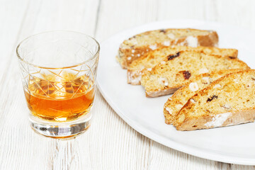 Italian biscotti cookies in white plate and sweet wine Vin Santo.
