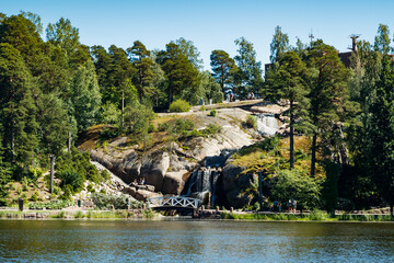 Fototapeta na wymiar Waterfall cascading over rocks in Sapokka landscaping park Kotka, Finland.