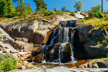 Fototapeta na wymiar Waterfall cascading over rocks in Sapokka landscaping park Kotka, Finland.