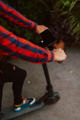 Closeup of hands of a young caucasian man with e scooter on the street