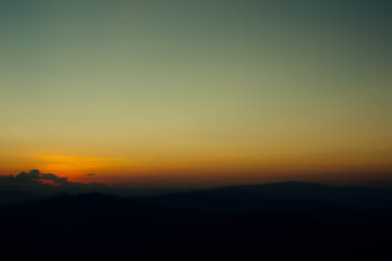 View of silhouatte of mountain range under the sky during the sunset. Beautiful evening nature background.