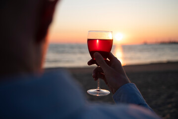 Man with glass of wine on beach at sunset