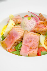Tuna salad with egg, tomatoes and salad on a white plate. Lunch at the restaurant.
