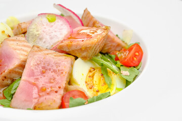 Tuna salad with egg, tomatoes and salad on a white plate. Lunch at the restaurant.