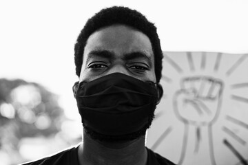 Young black man wearing face mask during equal rights protest - Concept of demonstrator on road for Black Lives Matter campaign - Focus on eyes - Black and white editing