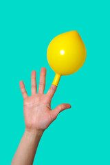 Hand with a cheerful yellow balloon on the index finger. Isolated on background.
