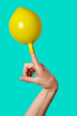 Hand with a cheerful yellow balloon on the index finger. Isolated on background.