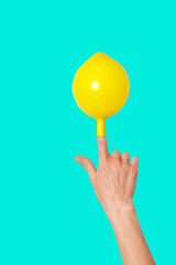 Hand with a cheerful yellow balloon on the index finger. Isolated on background.