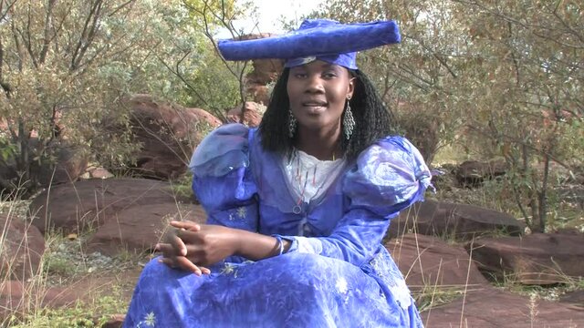 herero woman wearing a Victorian style dress outdoors in a village in north Botswana