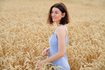 Young beautiful woman walking in golden wheat field at sunset. Freedom concept