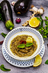 Eggplant dip baba ganoush (mutabbal) or mezze with ripe vegetables and fresh herbs