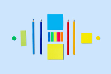 Blue background with writing materials. Back to school flat lay with colored pencils, paper clips, and stickers.