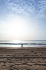 Fototapeta na wymiar Mujer paseando por la playa al amanecer en verano