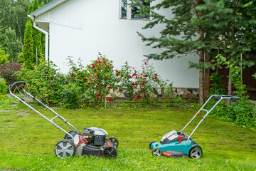 Black gasoline lawn mower versus green electric lawn mower