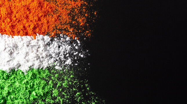 Indian Independence Day celebration background concept. Symbolic flag colors, red, green and orange powders colour splashed over dark background.
