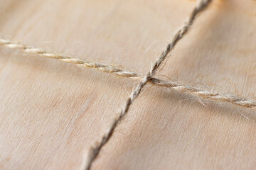 Wooden background drawn by a waxed cord. Light wood texture and rope crosswise in rustic style....