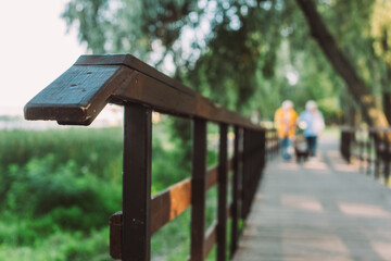 Selective focus of wooden bridge and couple walking in park