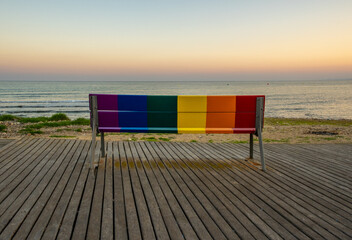 bench with the gay pride flag overlooking the sea.