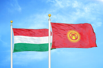 Hungary and Kyrgyzstan two flags on flagpoles and blue cloudy sky