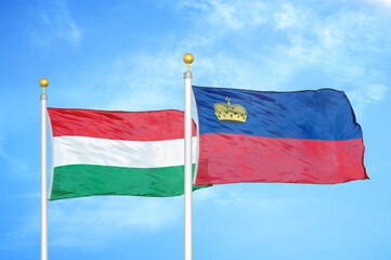 Hungary and Liechtenstein two flags on flagpoles and blue cloudy sky