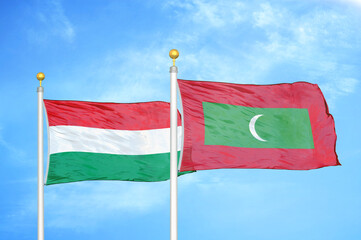 Hungary and Maldives two flags on flagpoles and blue cloudy sky