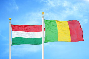 Hungary and Mali two flags on flagpoles and blue cloudy sky