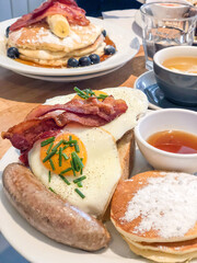 breakfast with egg, pancakes and sausage on table