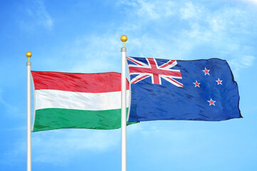 Hungary and New Zealand two flags on flagpoles and blue cloudy sky