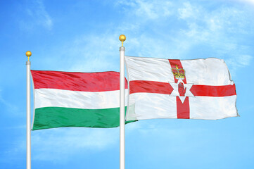 Hungary and Northern Ireland two flags on flagpoles and blue cloudy sky