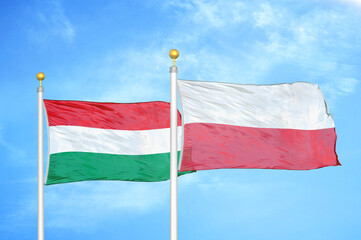 Hungary and Poland two flags on flagpoles and blue cloudy sky