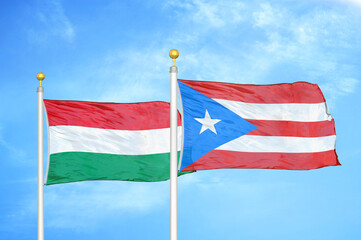 Fototapeta na wymiar Hungary and Puerto Rico two flags on flagpoles and blue cloudy sky