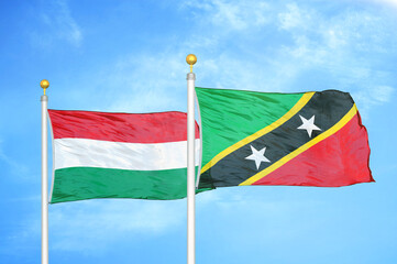 Hungary and Saint Kitts and Nevis two flags on flagpoles and blue cloudy sky