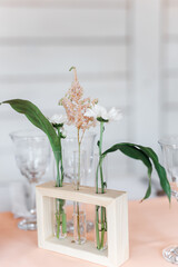 fresh flowers in glass flasks on a wooden stand