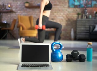 Blank screen laptop and fitness equipments at home. Concepts about online workout program, fitness video, home workout.