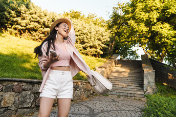 Image of asian girl using mobile phone and earphones while dancing