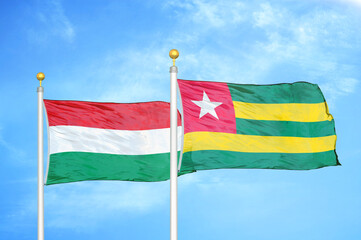 Hungary and Togo two flags on flagpoles and blue cloudy sky