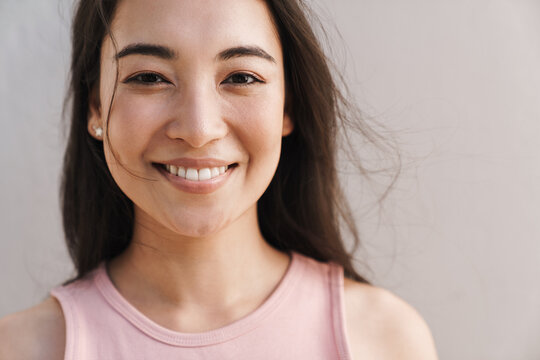 Image of joyful asian beautiful girl smiling with eyes closed