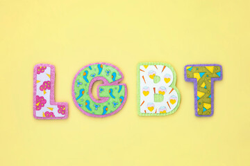 Craft LGBT letters on yellow background. Diversity, lgbt concept. Geometric patterns.