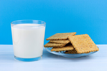 glass of milk and a plate of cookies on a blue background