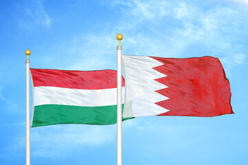 Hungary and Bahrain  two flags on flagpoles and blue cloudy sky