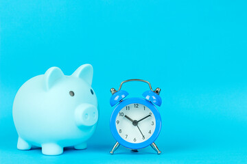 piggy bank in the form of a pig on a blue background with an alarm clock