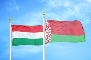 Hungary and Belarus  two flags on flagpoles and blue cloudy sky