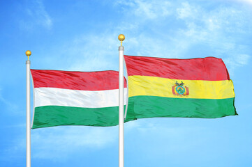 Hungary and Bolivia  two flags on flagpoles and blue cloudy sky